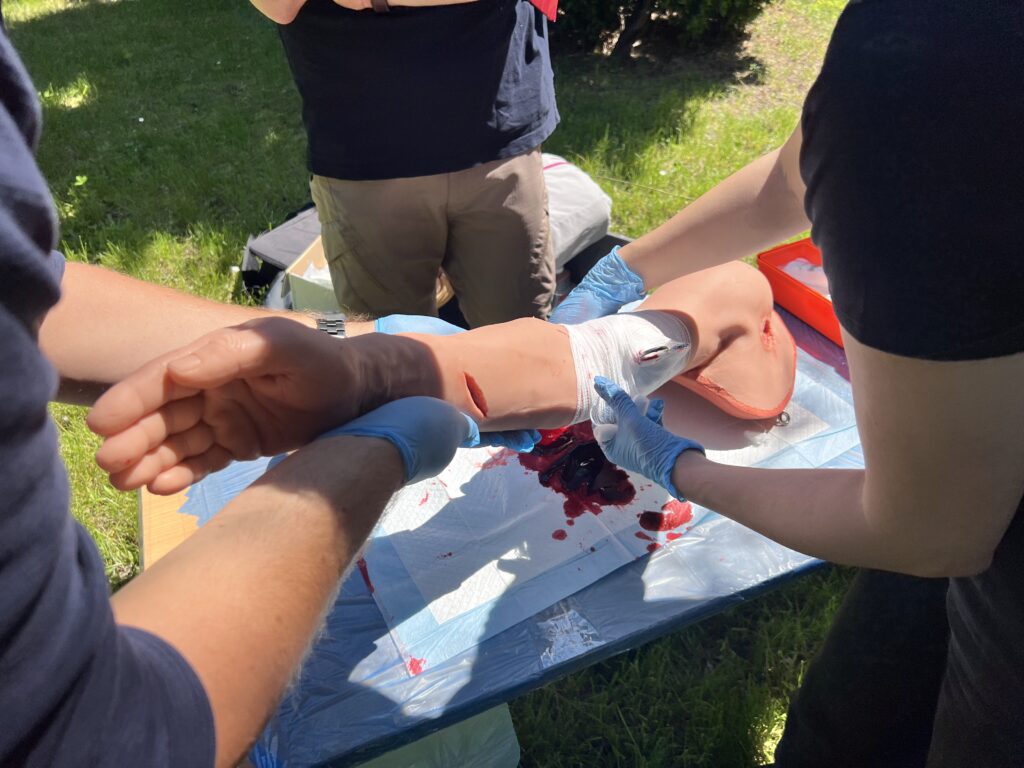 Grupa uczestników warsztatów opatruje ranę