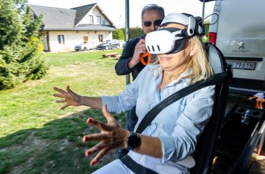 Symulator zderzenia VR Kobieta w goglach VR uczestniczy w realistycznej symulacji wypadku drogowego, siedząc w symulatorze zderzenia, obok instruktor bezpieczeństwa.